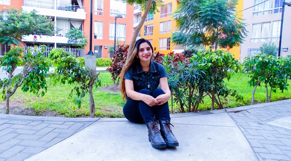 woman sitting on concrete surface near plants during daytime