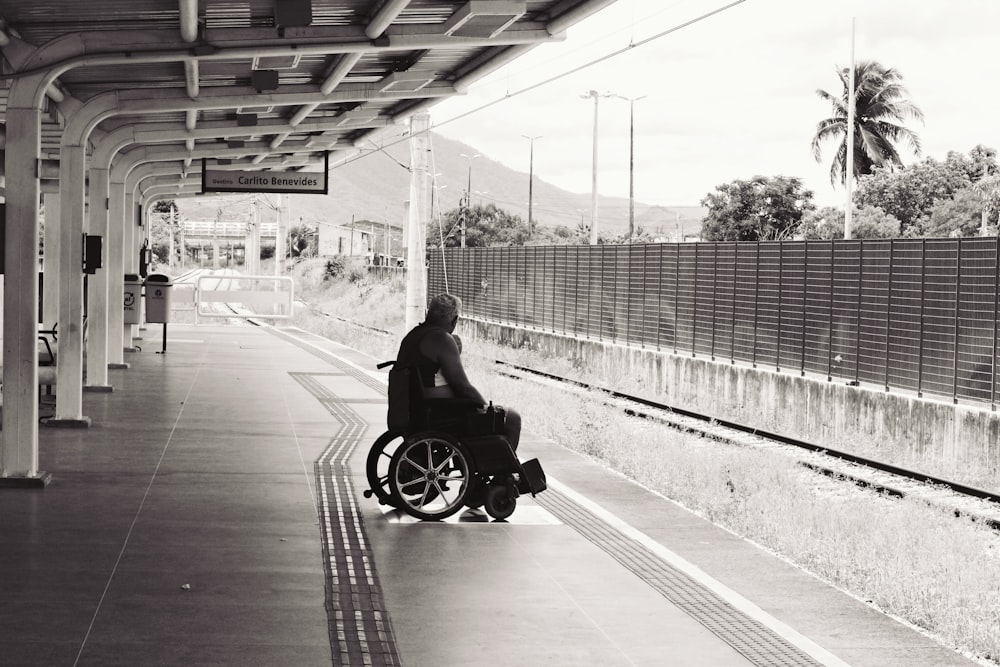 grayscale photo of person sitting on wheelchair