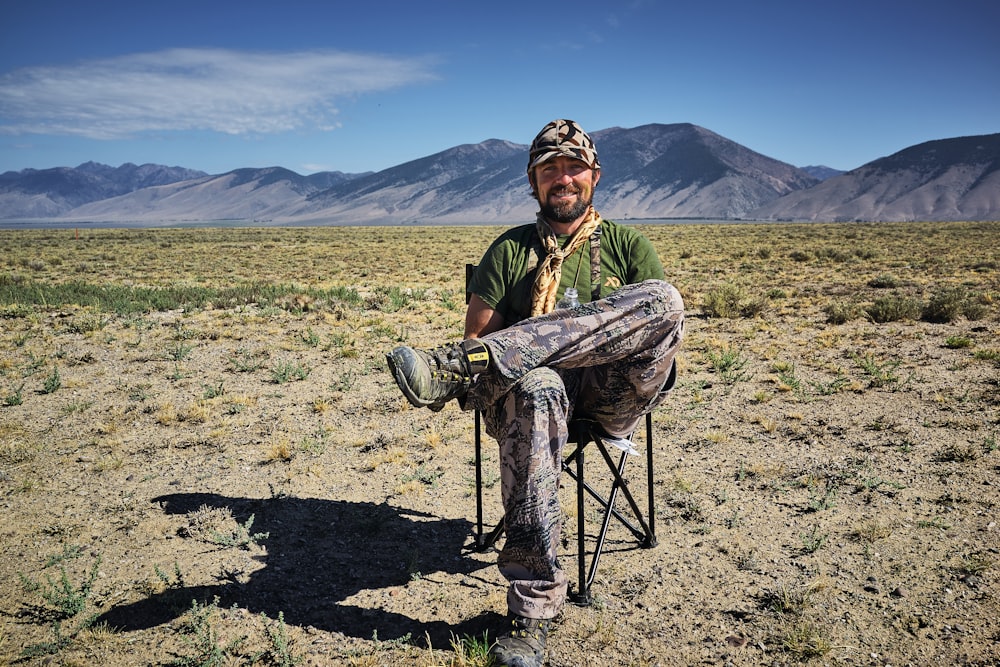 man sitting on folding camping chair in the middle of desert