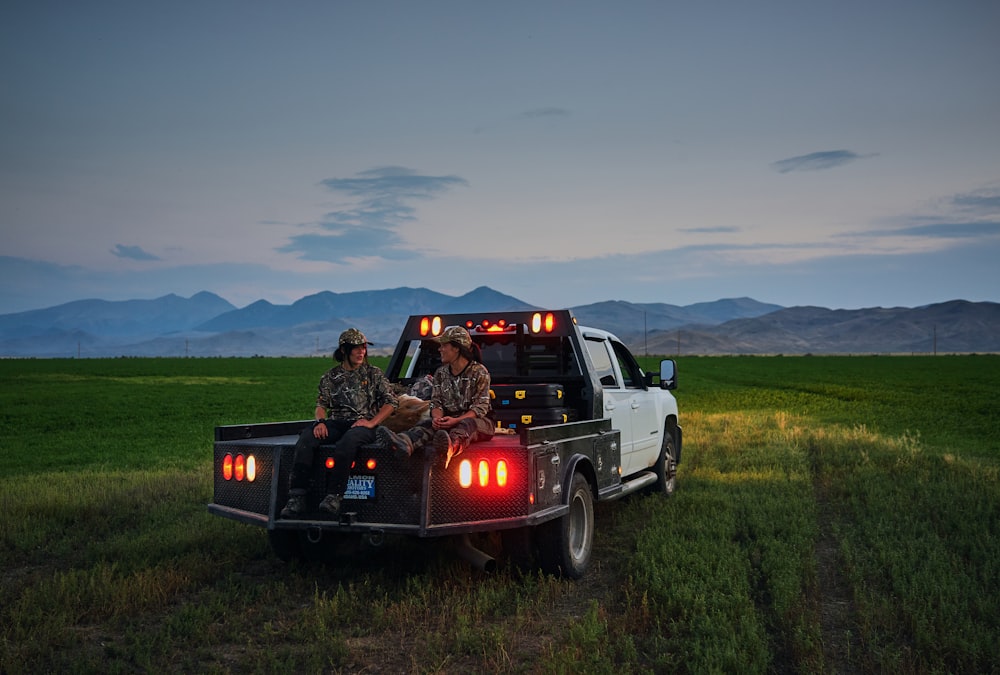 two person sits at the back of pickup truck