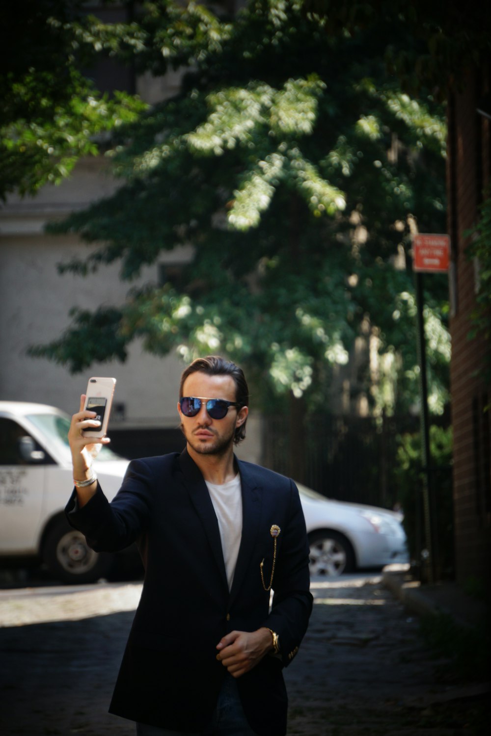 a man walking down a street holding up a cell phone