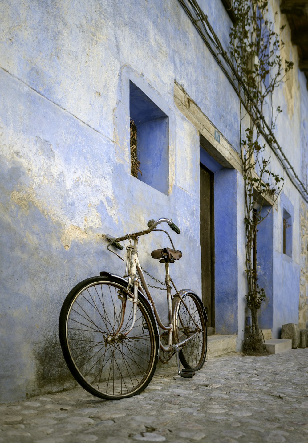 beige city bike parked and leaning on concrete wall