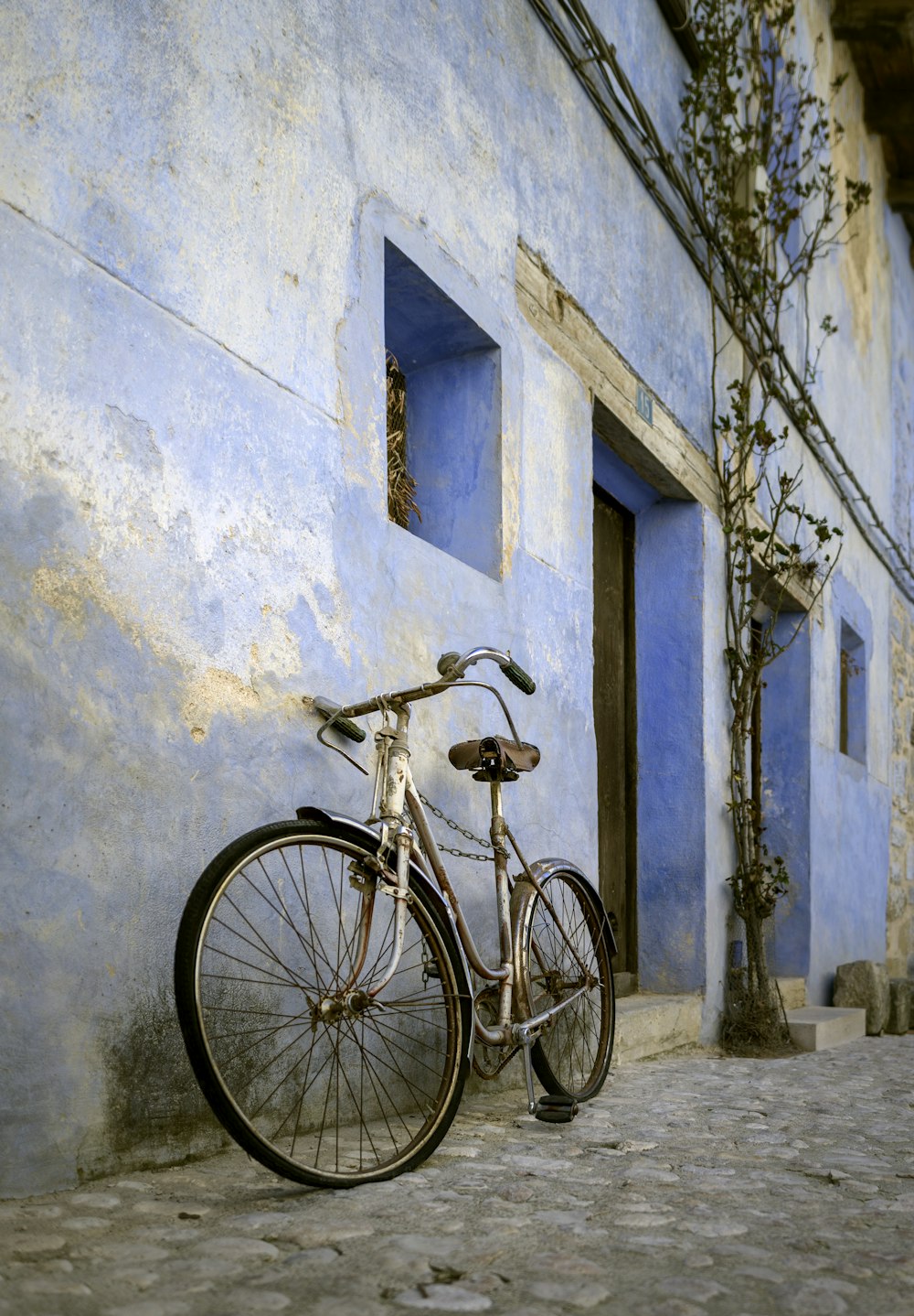Vélo de ville beige garé et appuyé sur un mur en béton