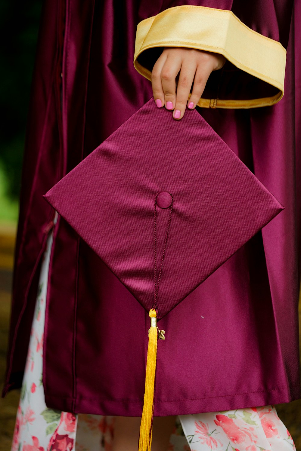 woman holding purple mortar board wearing toga