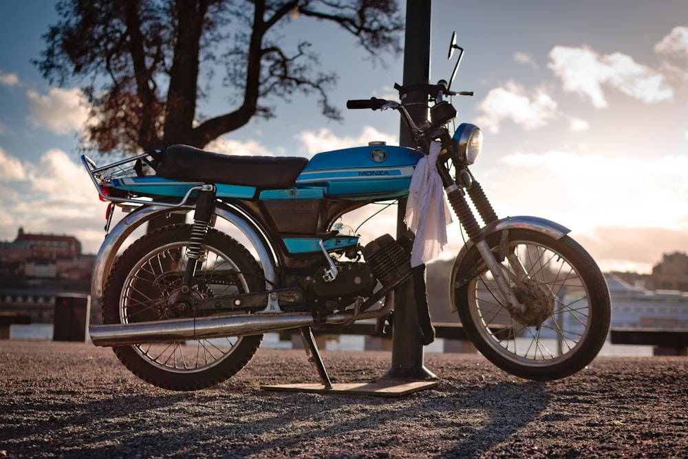 a blue motorcycle parked on top of a dirt field