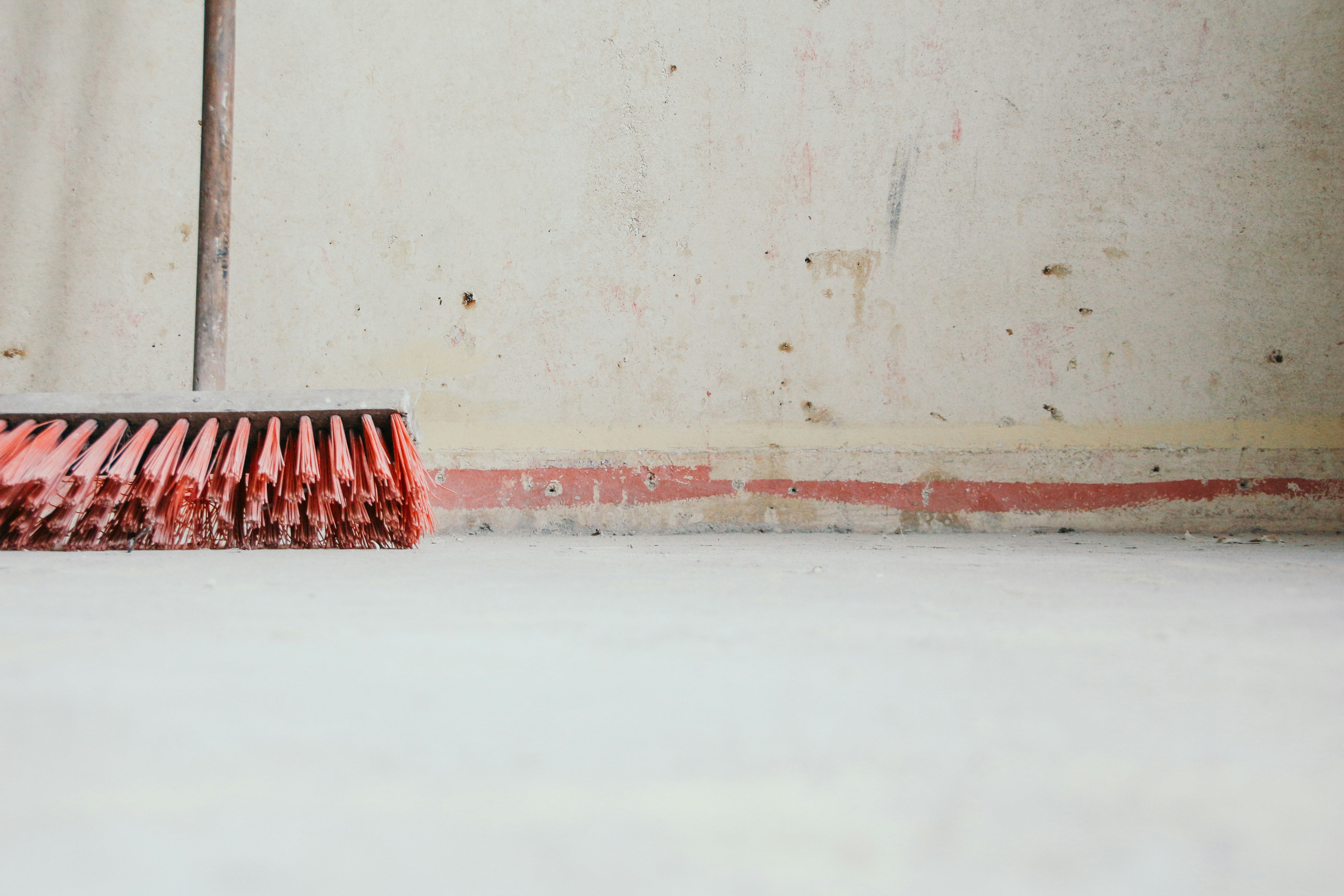 red push broom beside wall