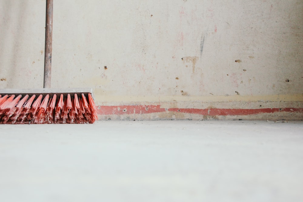 red push broom beside wall