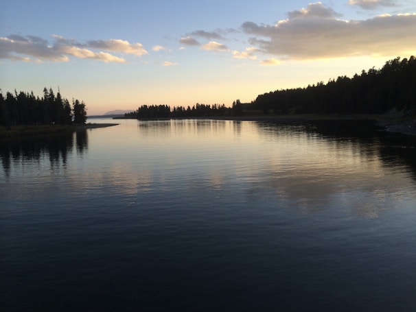 A serene enchanted lake reflecting colorful magical effects at sunset.
