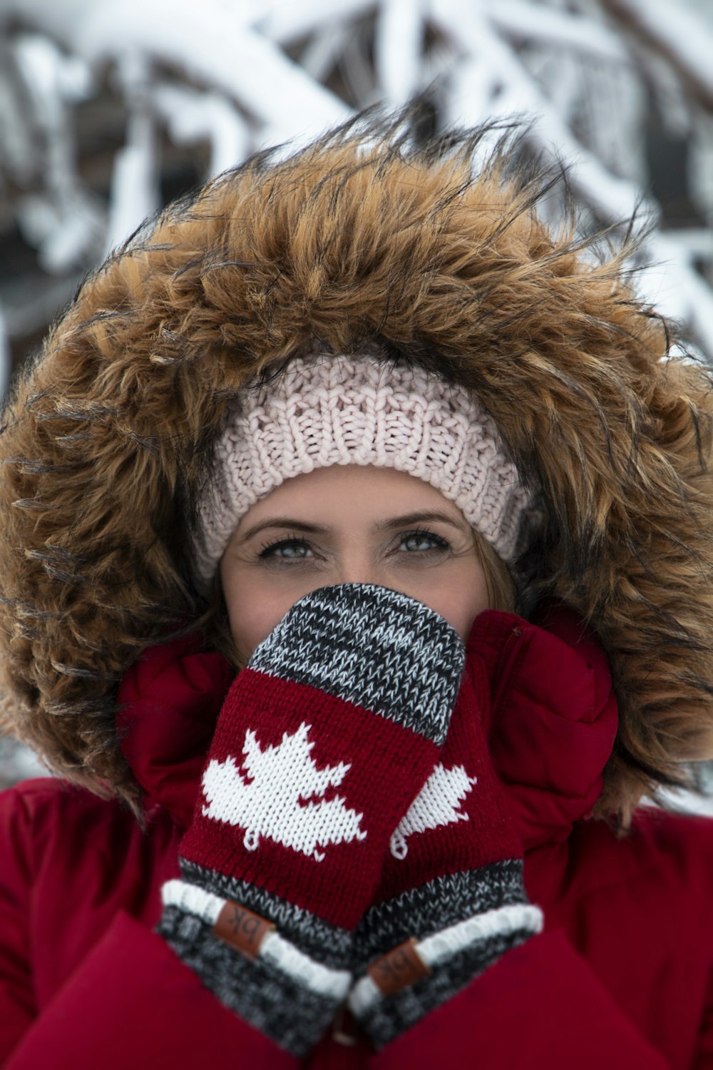 woman wearing red-and-brown parka coat and gray-and-red Canada knit mittens