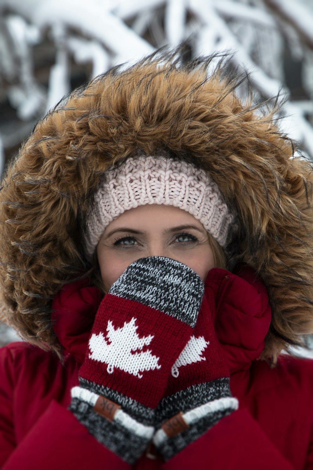 mujer con abrigo parka rojo y marrón y manoplas de punto Canadá grises y rojas