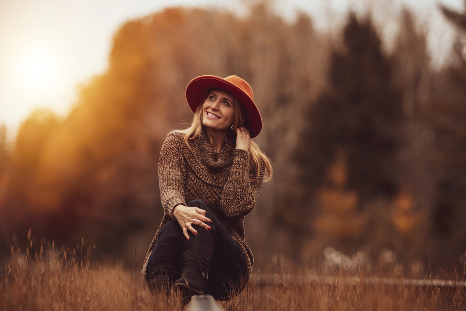 Femme souriante en pull et chapeau de feutre dans un décor d’automne