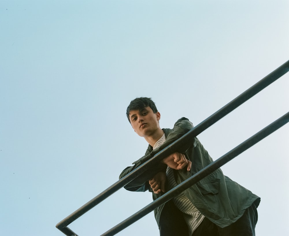 man in gray jacket standing leaning on rails