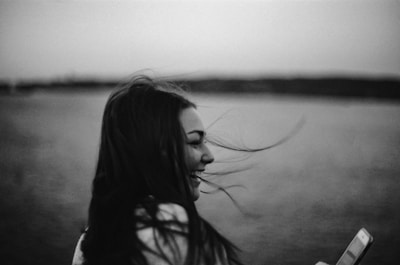 grayscale photography of smiling woman holding smartphone