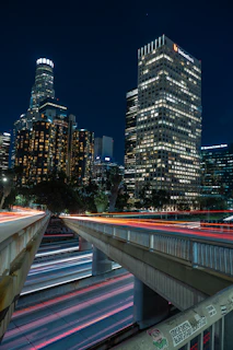 Urban skyline at night visible through studio windows, city lights framing an atmosphere of creative energy and business hustle.