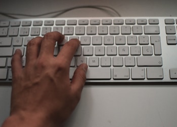 person's left hand on white Apple Magic Keyboard