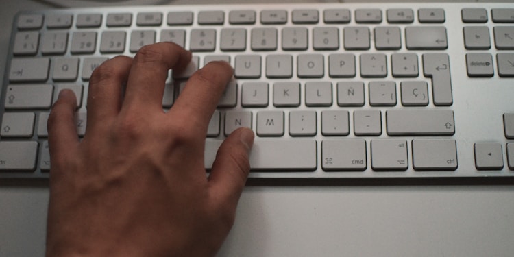 person's left hand on white Apple Magic Keyboard