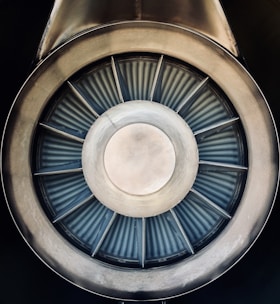 A close-up view of a jet engine turbine, displaying the concentric metallic blades and central hub with a symmetrical pattern.