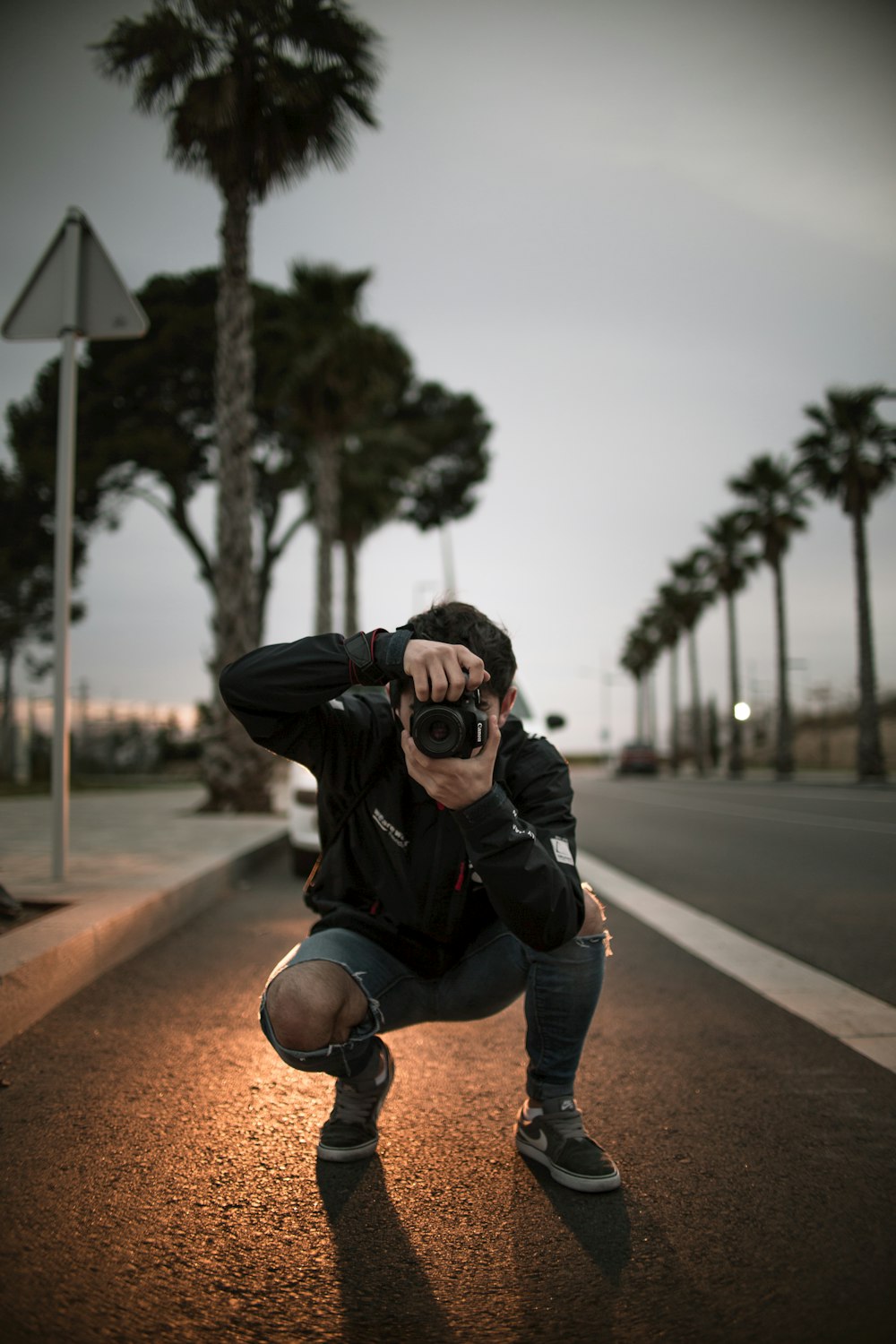 man wearing blue ripped jeans holding DSLR camera