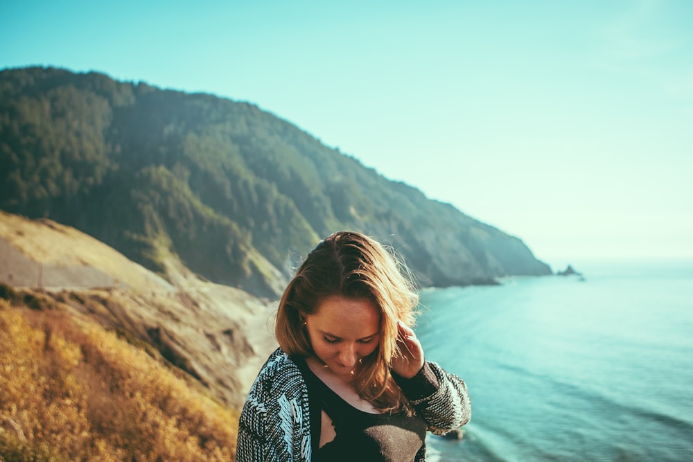 woman standing on cliff facing sea during daytime