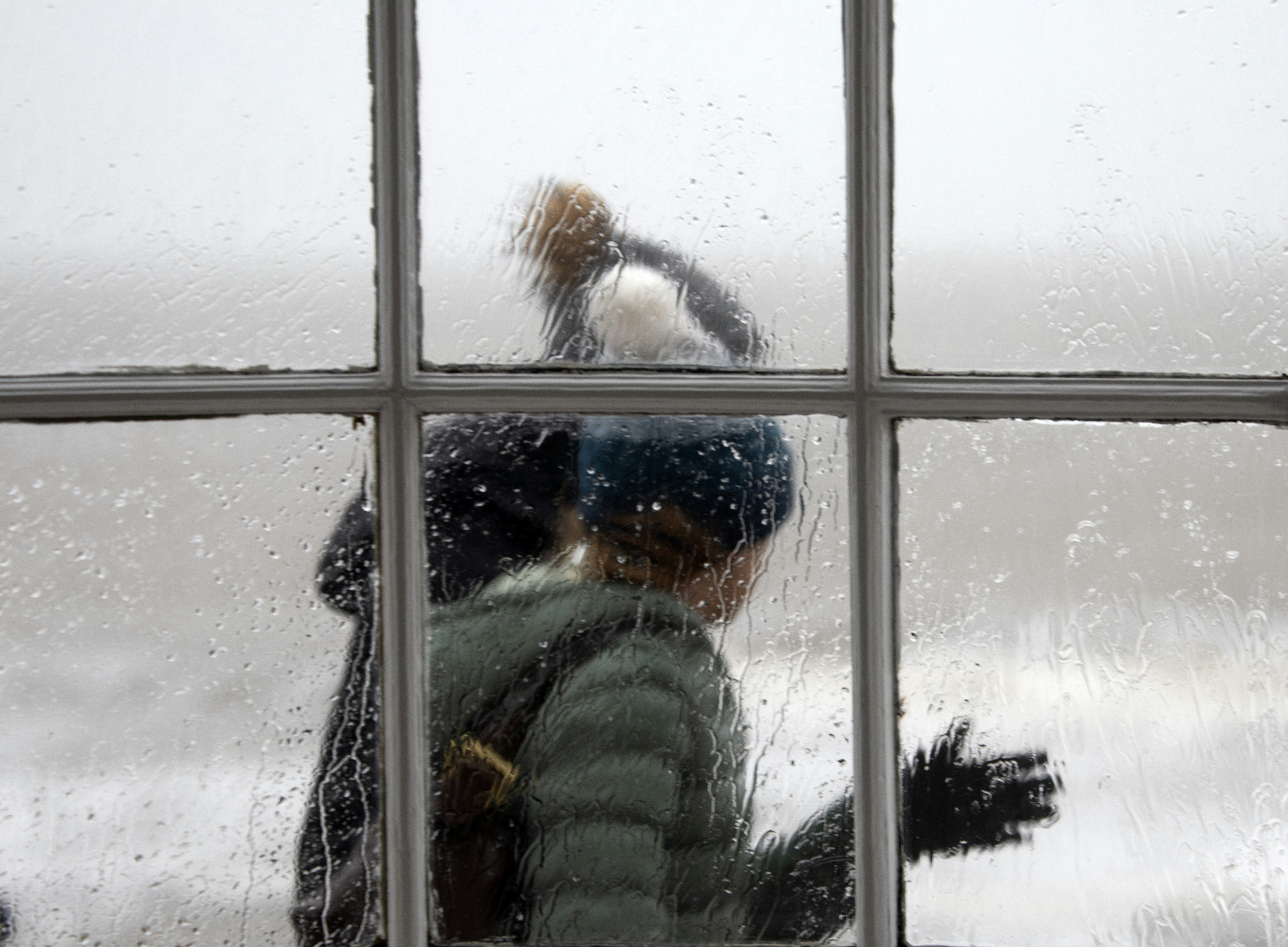 A person looking out a window at a snowy landscape