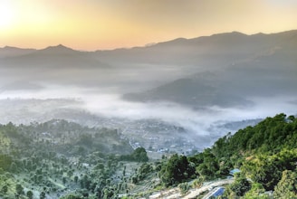 A panoramic view of the Rhodope Mountains at sunrise, with mist rolling over the valleys.