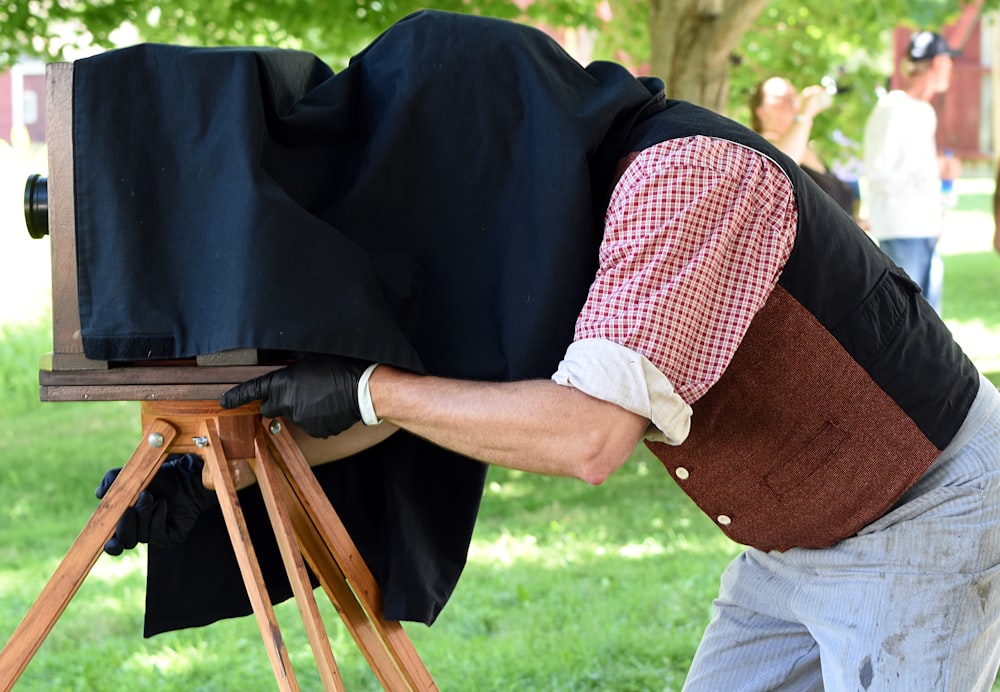 Hombre cubriendo su cabeza con tela negra mientras opera una cámara vintage
