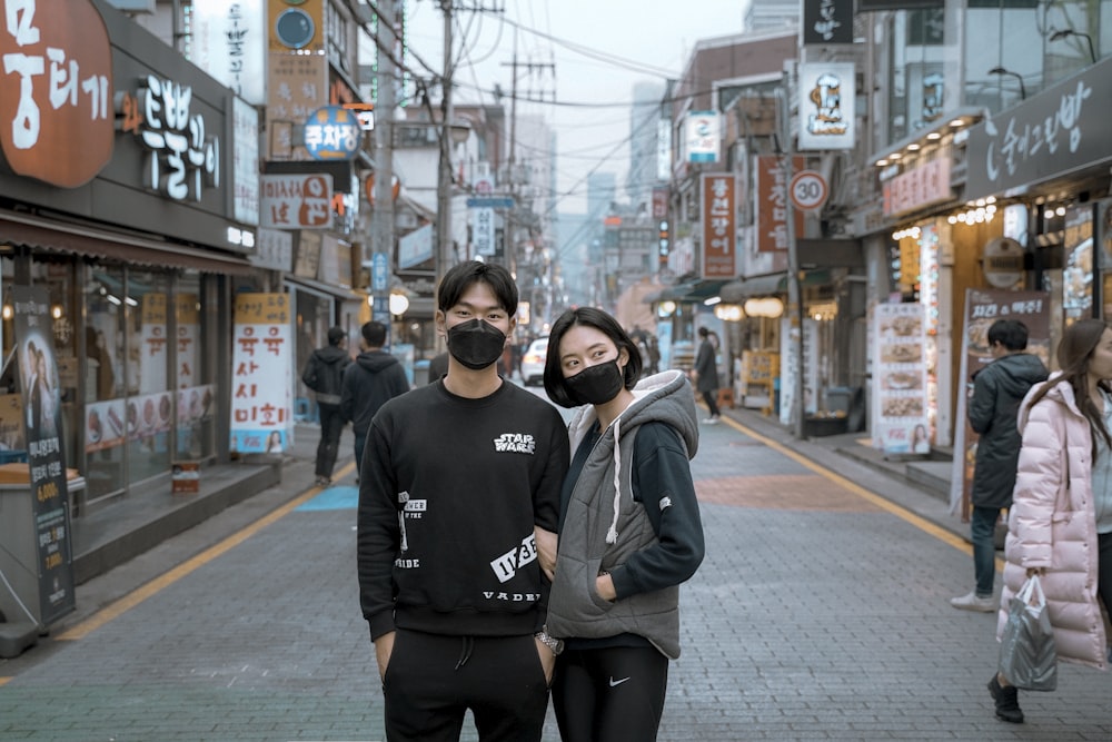 two man and woman wearing face mask in between building