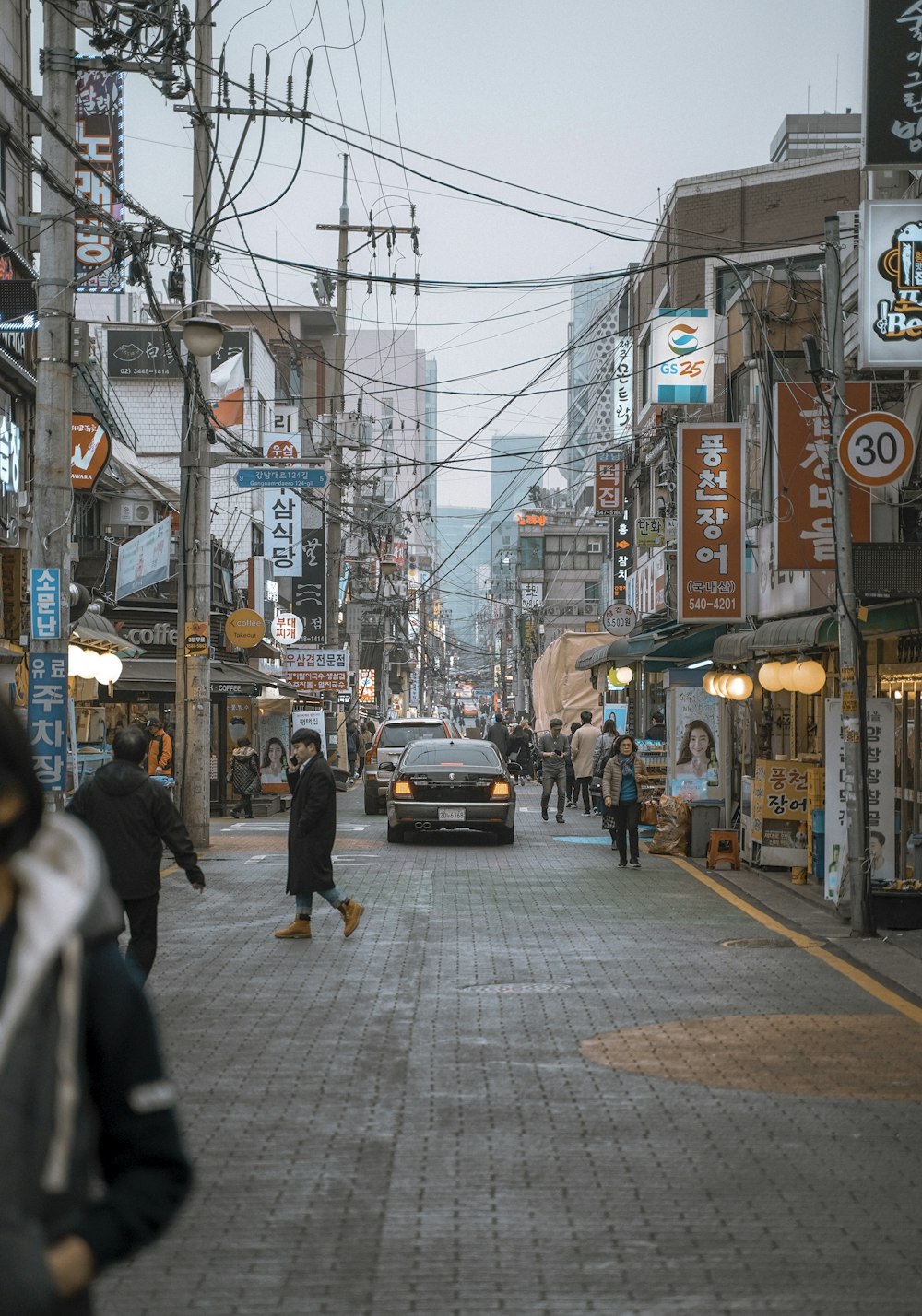 people walking by the streets with 2 cars in the middle