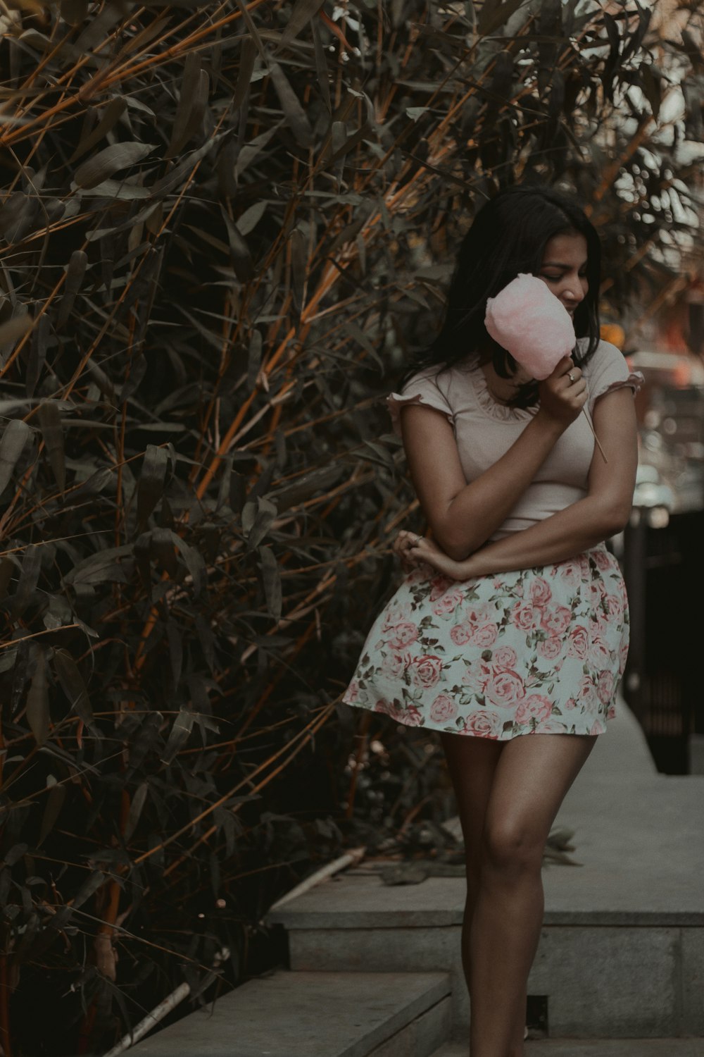 woman in beige top and floral skirt holding pink cotton candy