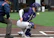 A young umpire in full gear attentively calling a play during a fastpitch game.