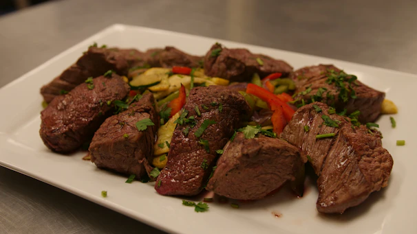 Plate of perfectly grilled steak garnished with fresh herbs and side dishes.
