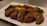 A beautifully grilled steak served on a wooden plate with fresh herbs.