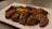 A beautifully grilled steak served on a wooden plate with fresh herbs.