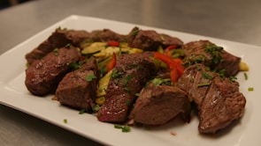 Grilled steak with herbs and a side of roasted vegetables on a ceramic plate.