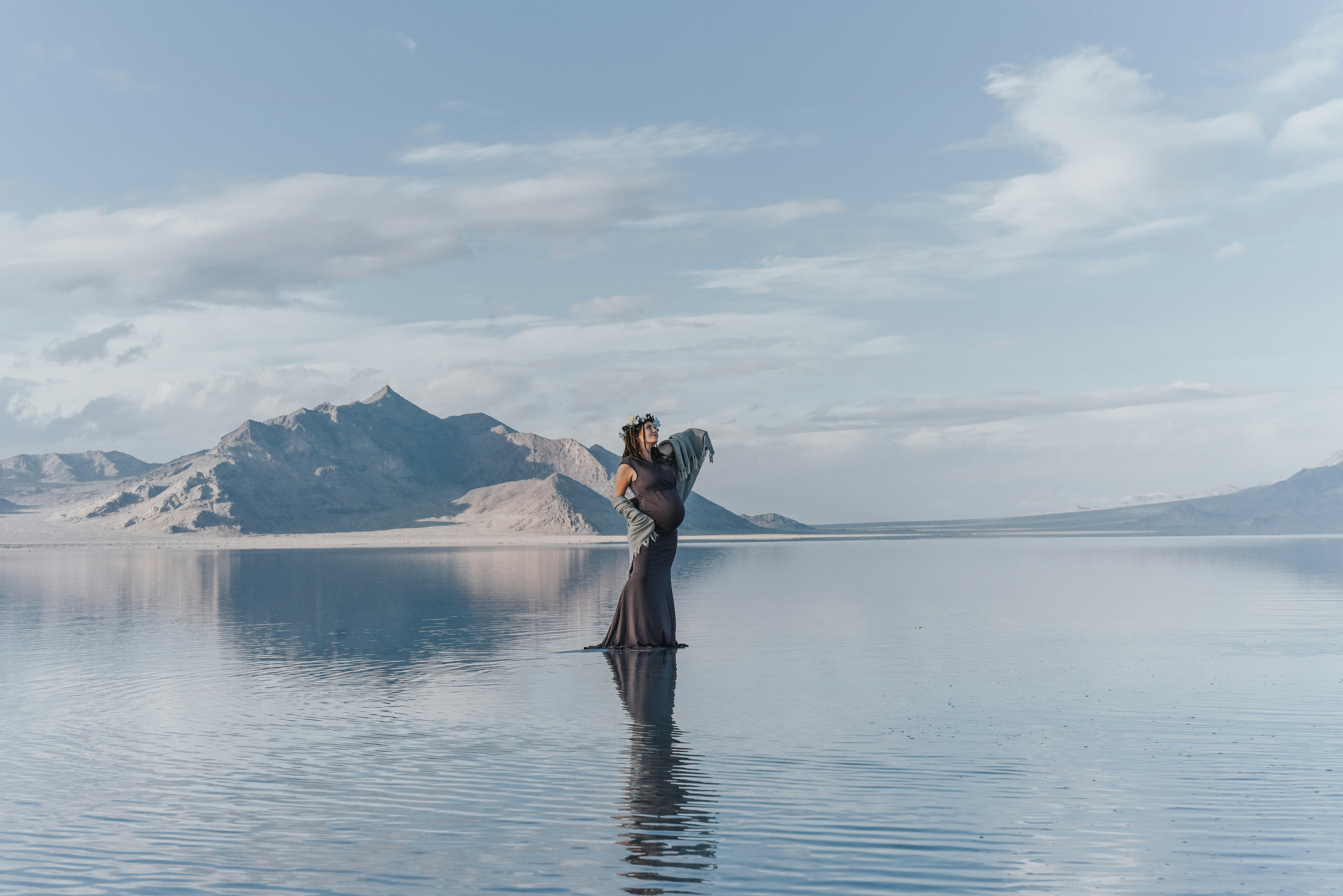 woman standing on body of water with mountains at the distance