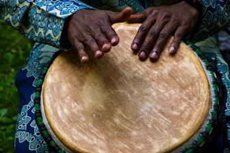 person tapping on traditional drum instrument