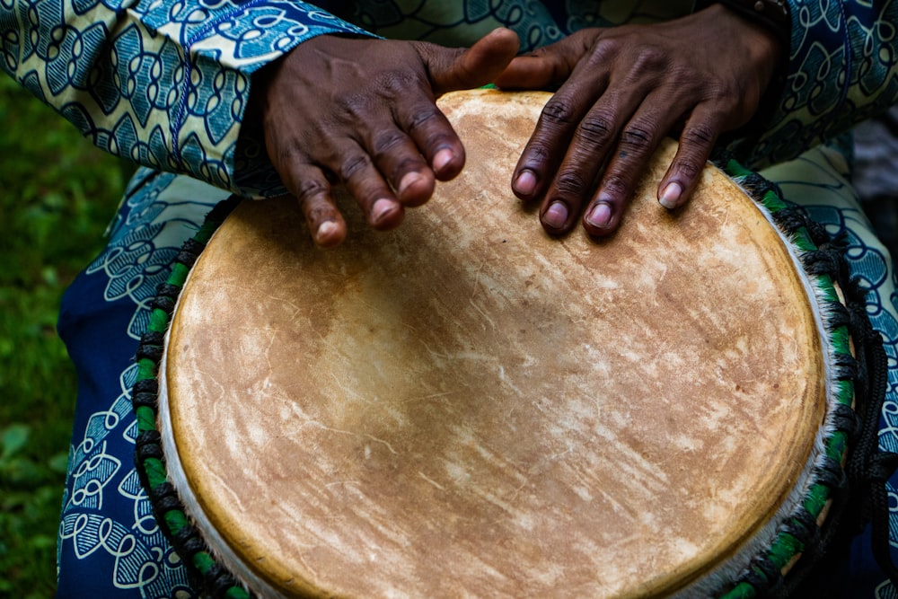 person tapping on traditional drum instrument