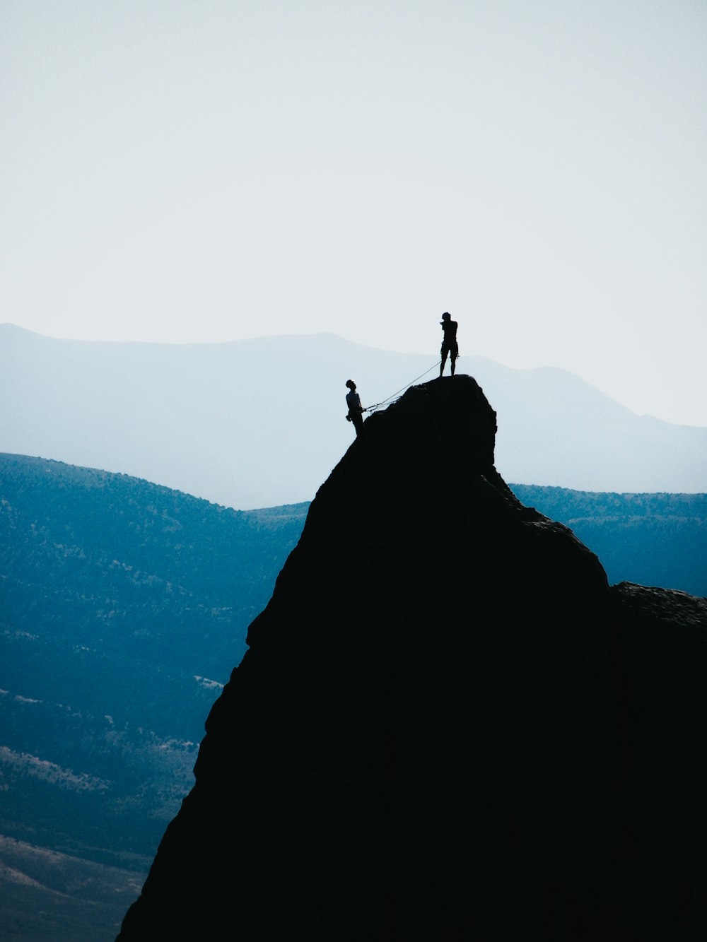 silhouette of two people standing on mountain during daytime