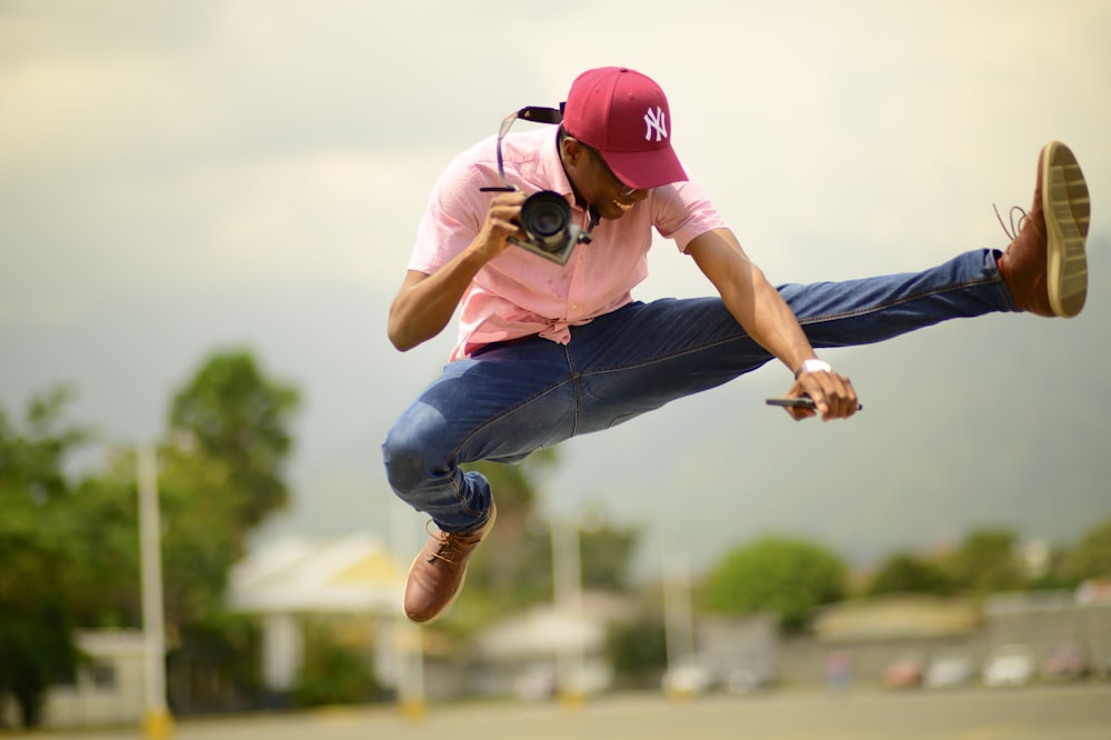 man jumping while holding camera