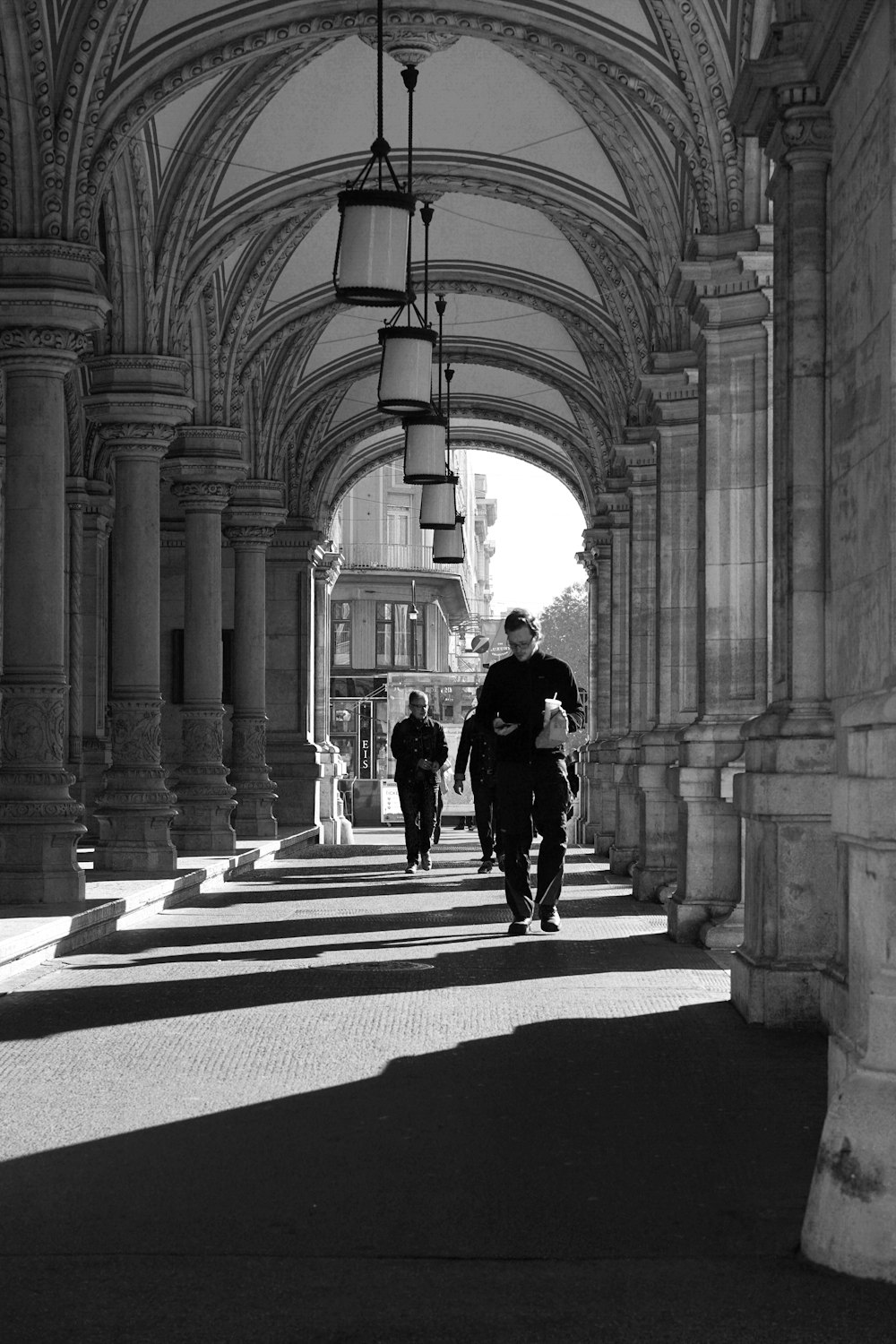 greyscale photo of man walking near pillars