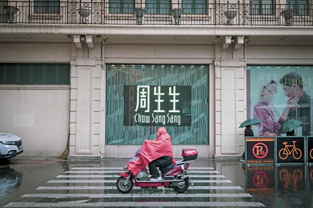 person riding red motor scooter