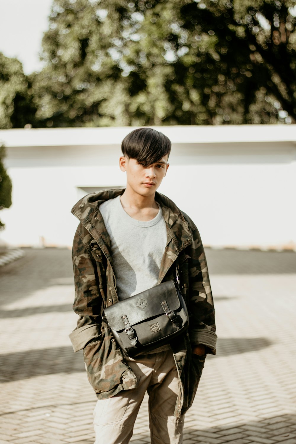 man wearing camouflage jacket carrying black leather satchel bag