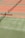 Several tennis courts with orange and green surfaces, separated by nets. Benches are placed alongside the courts.