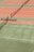 Several tennis courts with orange and green surfaces, separated by nets. Benches are placed alongside the courts.