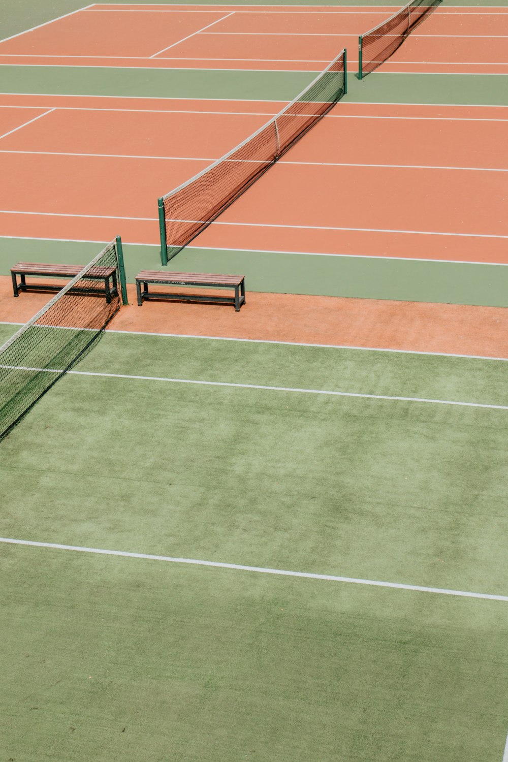 Campos de tenis verdes y naranjas vacíos