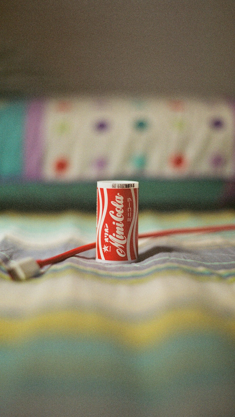 Mini Cola soda can on multicolored textile