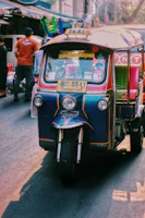 The tuk tuk banana food trailer decorated with bright Thai patterns parked at a sunny market.