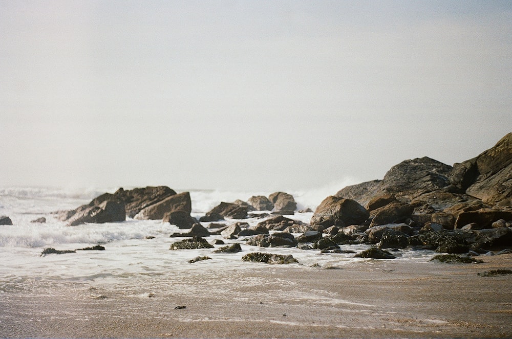 waves crashing on rocks at shore during daytime