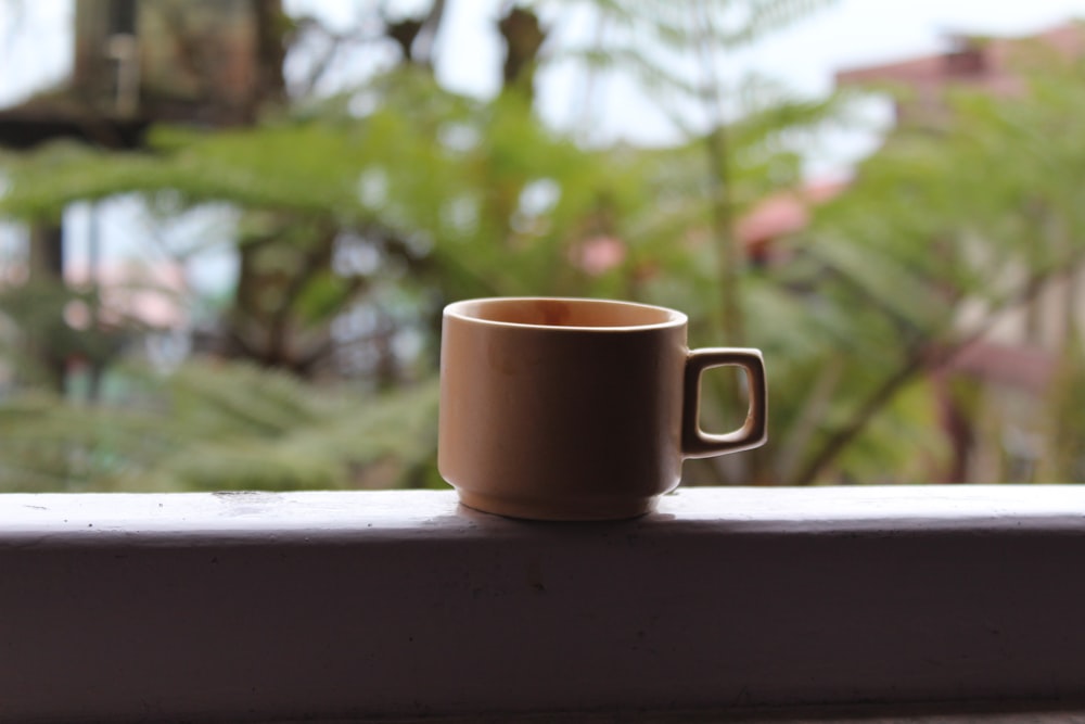 mug on white surface near leaves