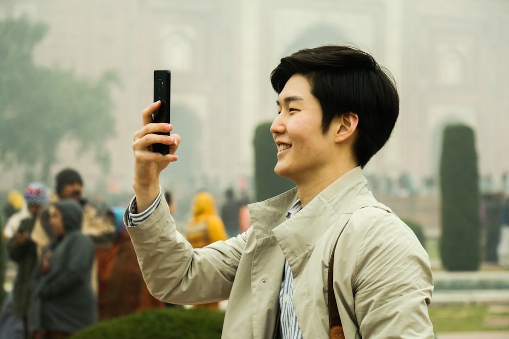 Hombre sosteniendo un teléfono inteligente durante el día